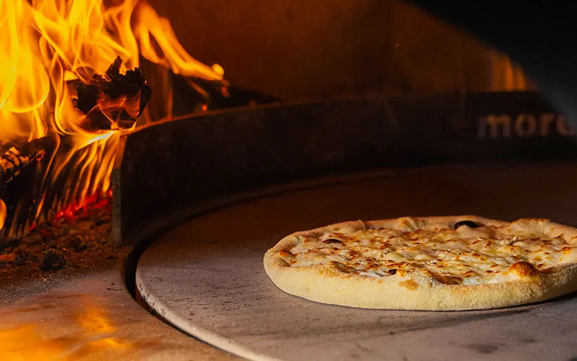 Une pizza qui sort du four à Bois